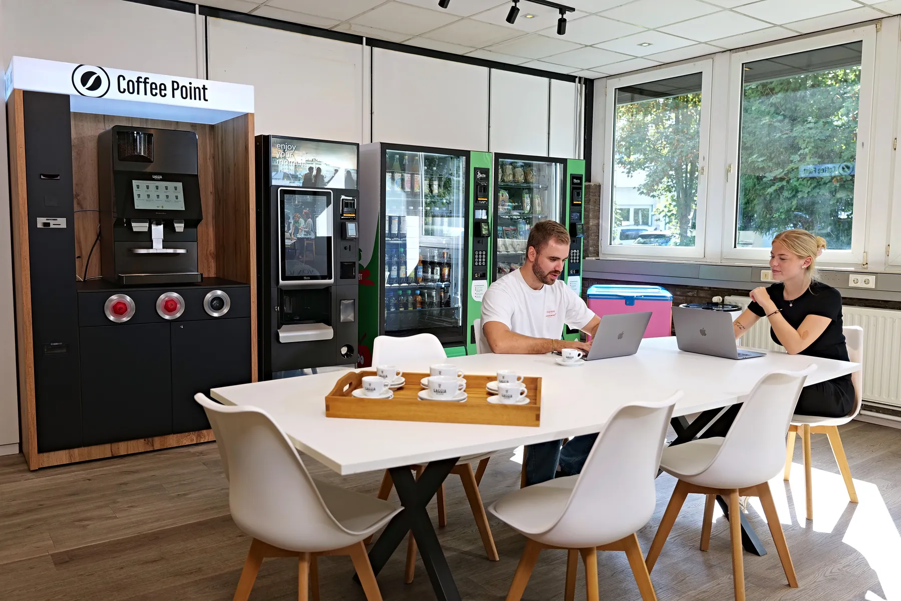 Mitarbeitende am Tisch vor Coffee Point und Local Life Automaten im Showroom