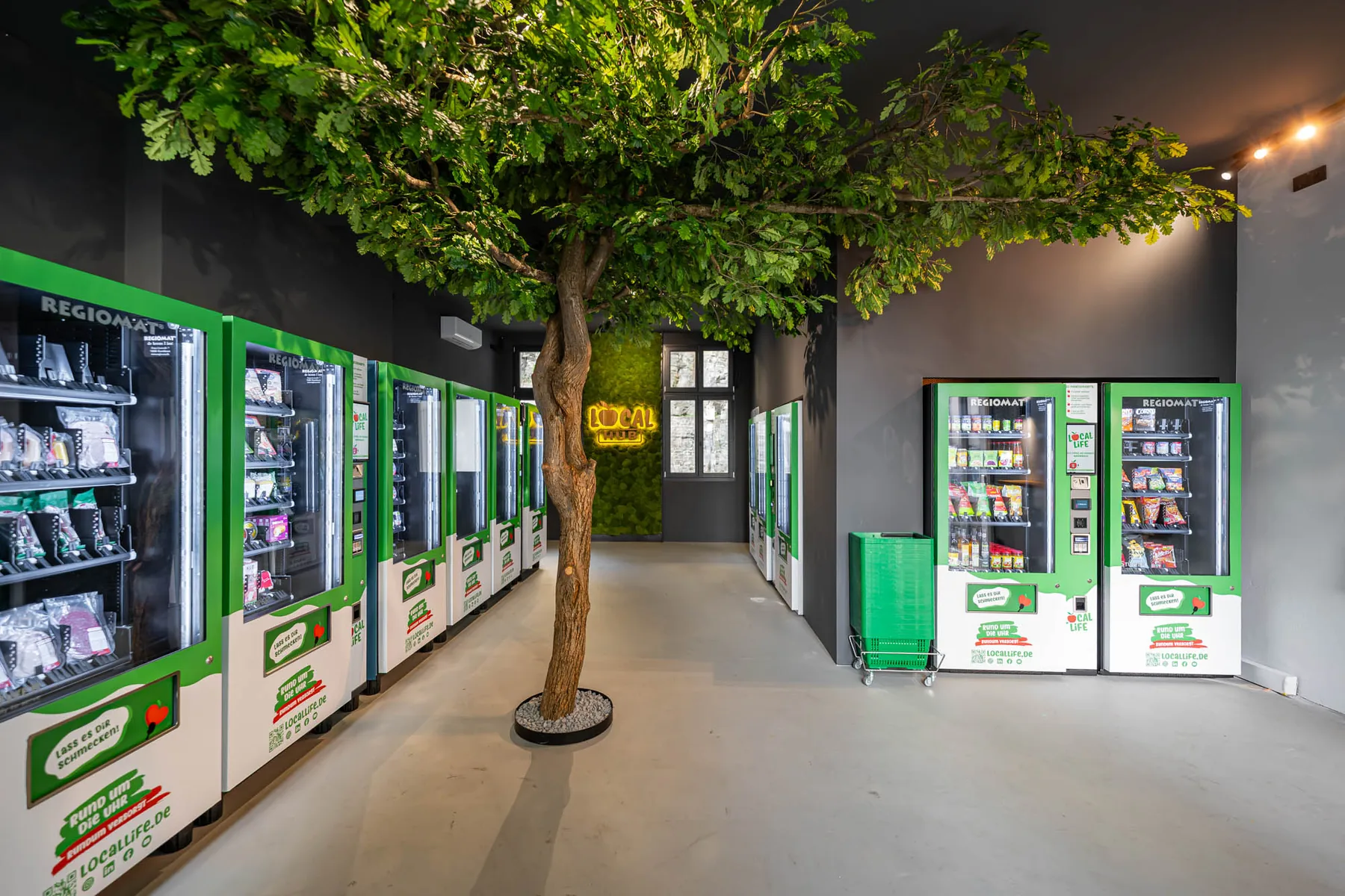 Innenansicht des Local Hub mit Automaten und Baum